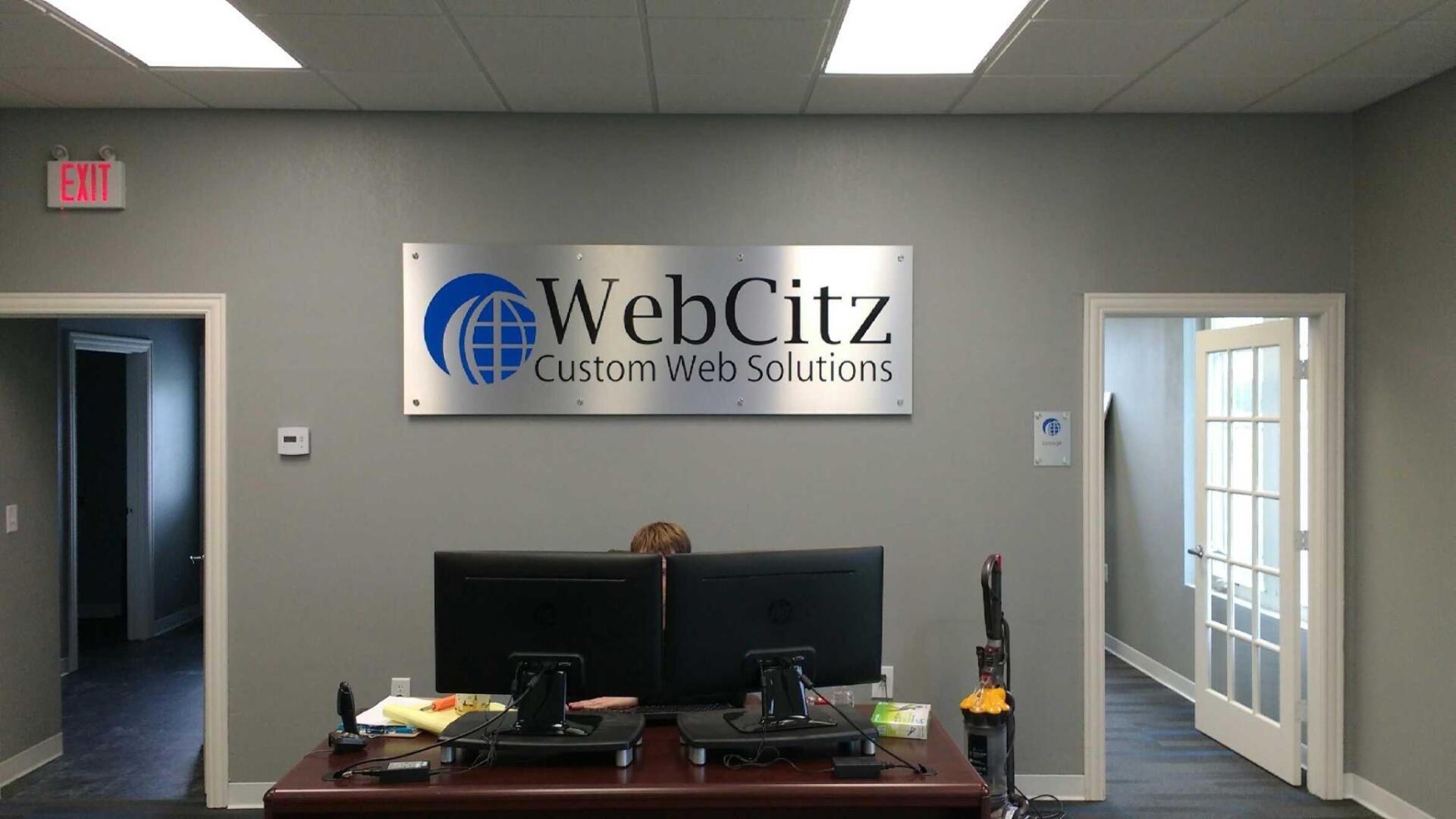 A sign on the wall says webcitz custom web solutions