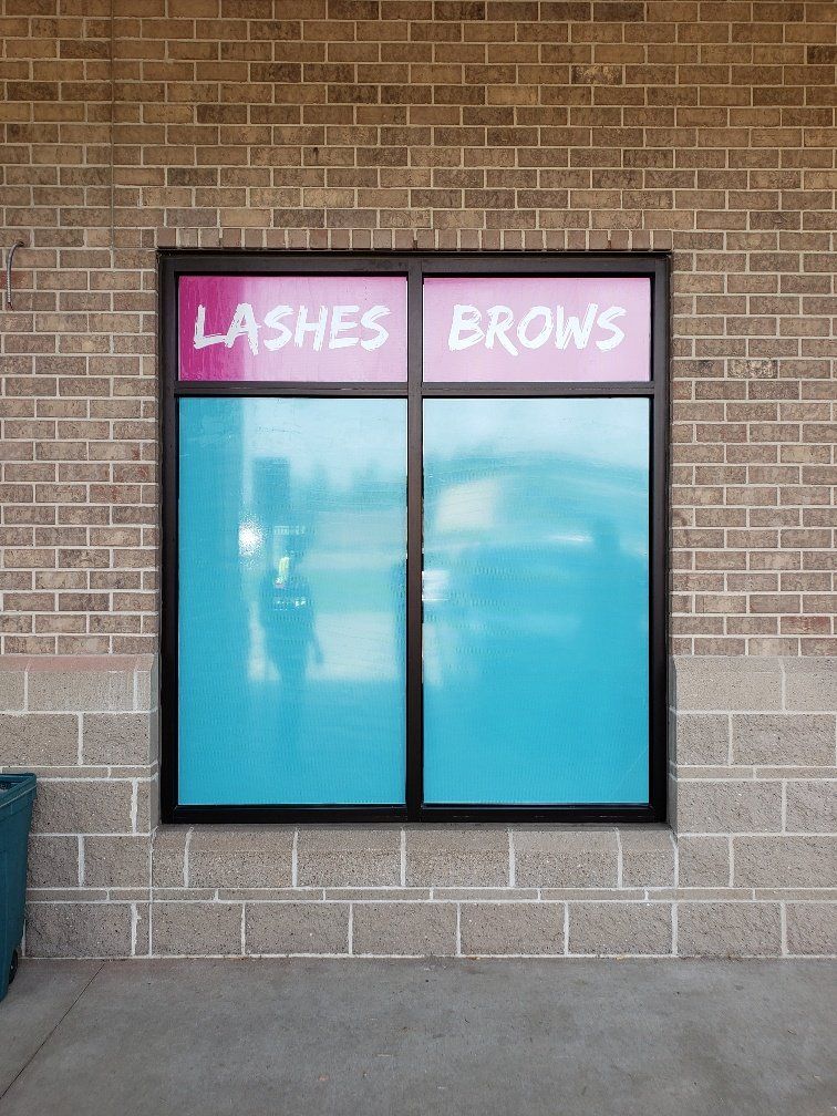 A brick building with a window that says lashes and brows