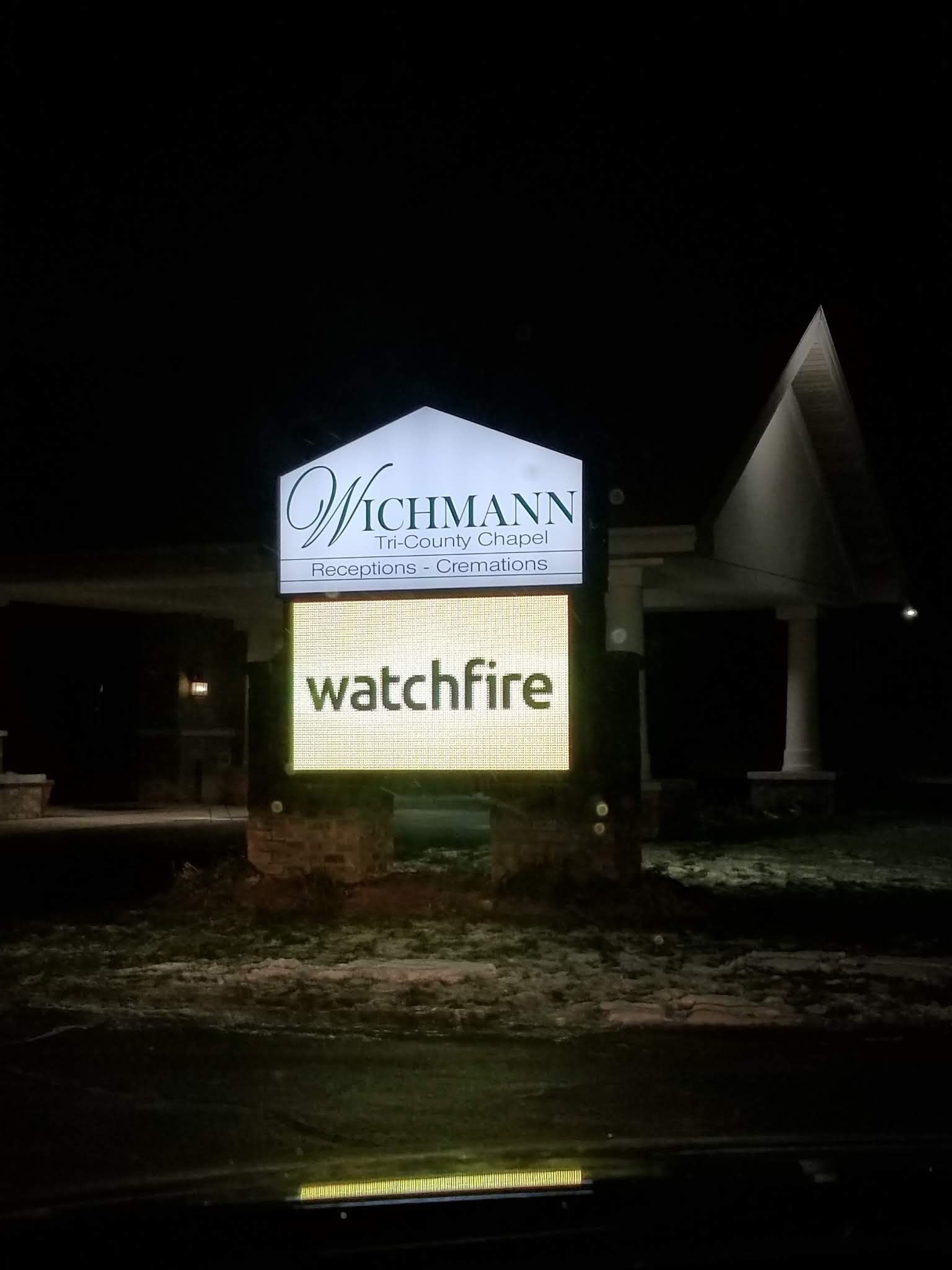 A sign that says watchfire is lit up at night.