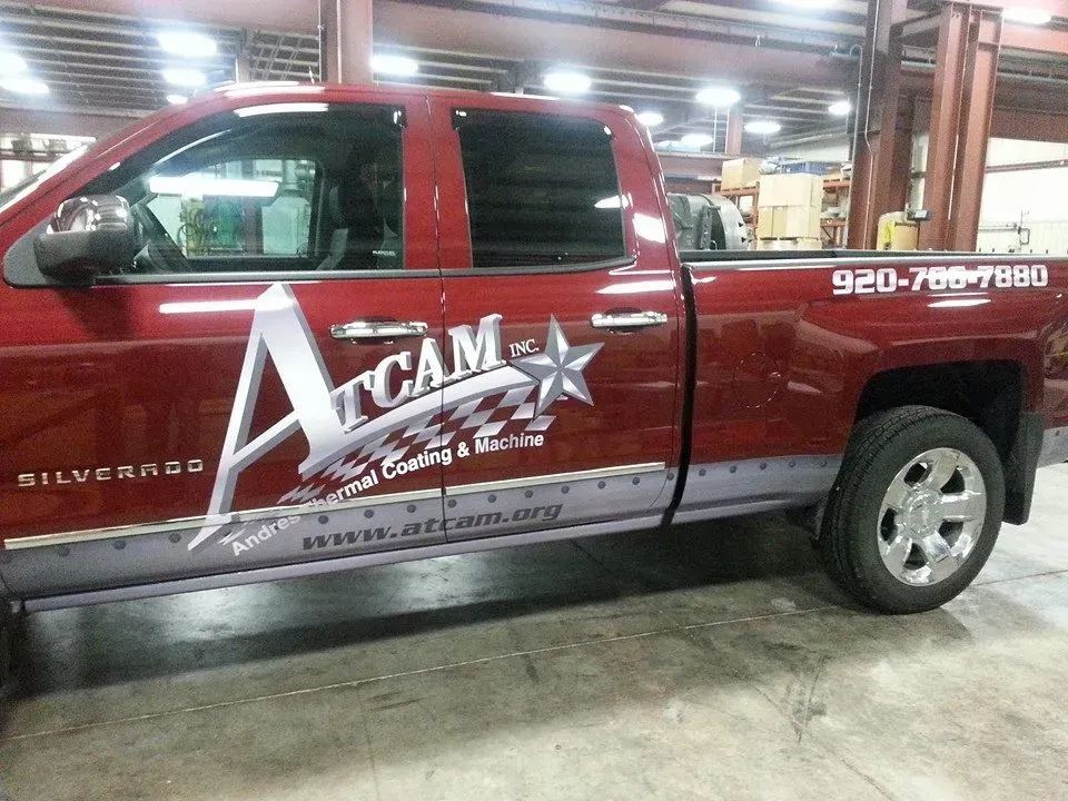 Red pickup truck with logo, side view, inside a warehouse.