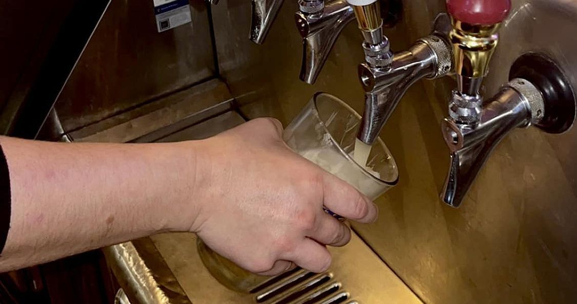 A person is pouring beer into a glass from a tap