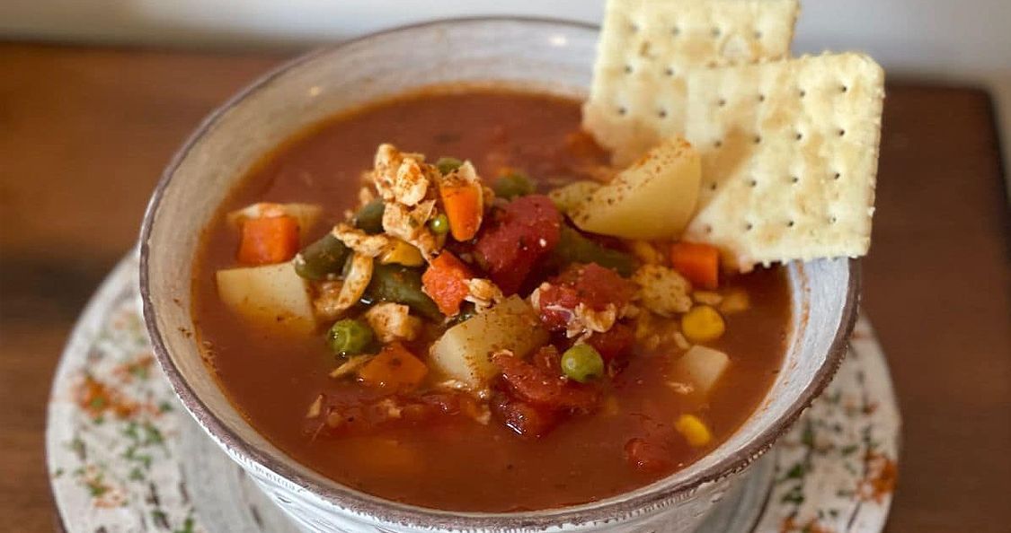 a bowl of soup with crackers on top of it on a plate .