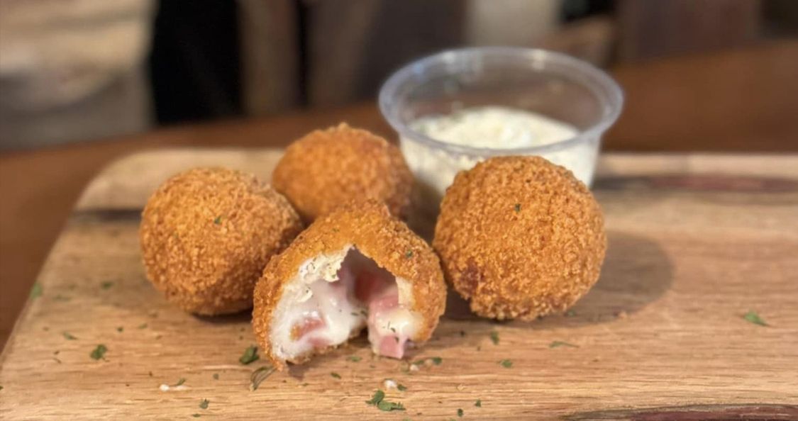 A wooden cutting board topped with fried food and a cup of ranch dressing