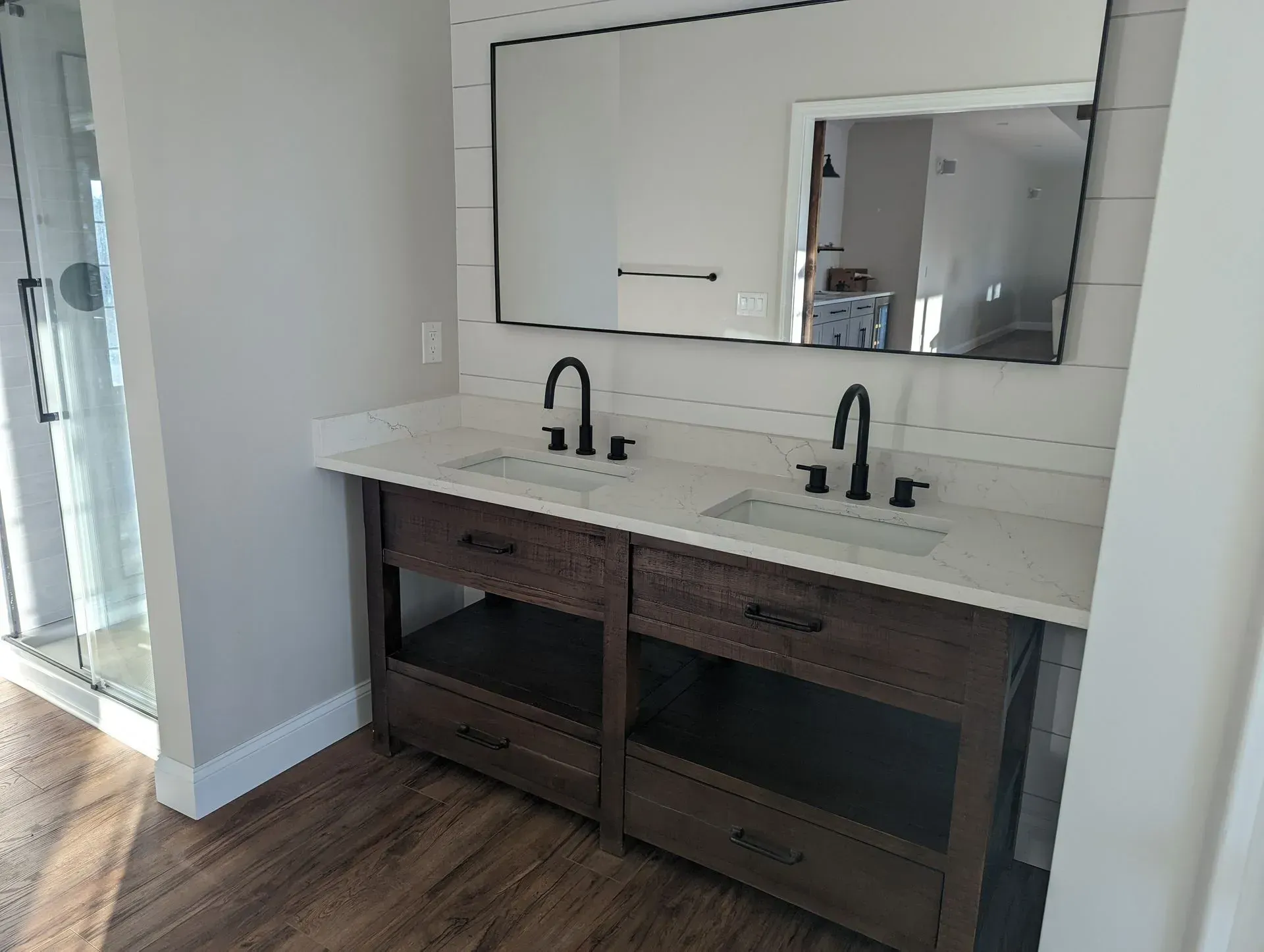 Modern double-sink bathroom vanity with white countertop, dark wood cabinets, and large mirror.