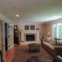 Spacious living room with fireplace, hardwood floors, sofa, coffee table, and large windows.