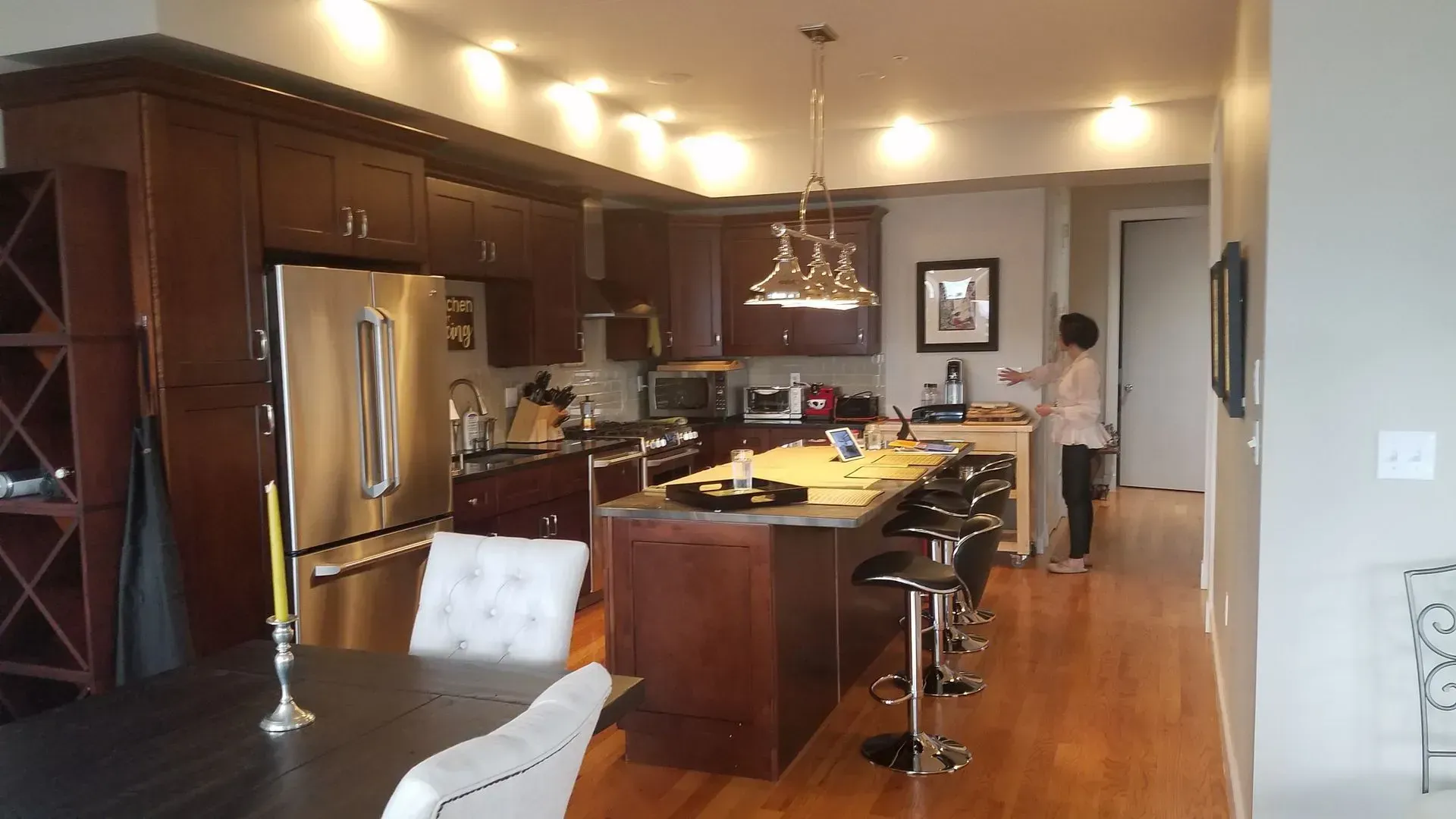 Modern kitchen and dining area with dark wood cabinets, island seating, and a person standing in the doorway