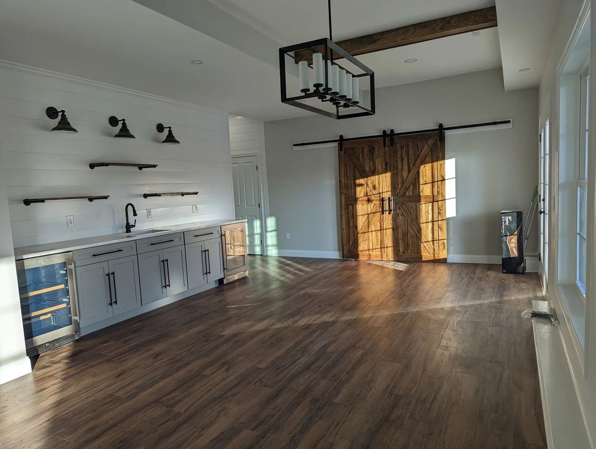 Empty modern kitchen with white cabinets, wood floors, and a large island in a bright open room