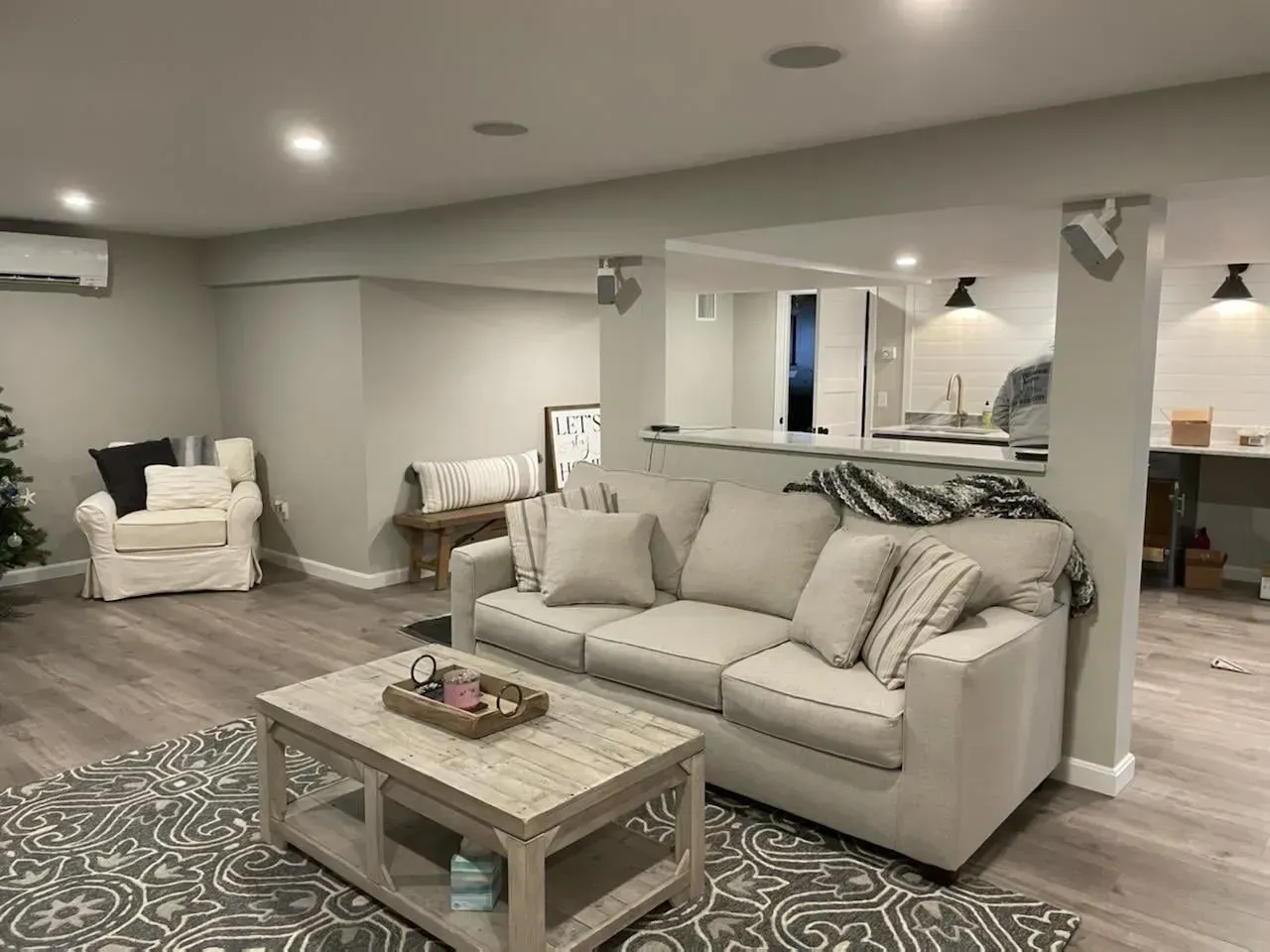 Modern living room with beige sofa, patterned rug, coffee table, and armchair in a finished basement
