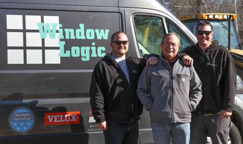 Three people standing beside a Window Logic van, smiling outdoors in daylight.