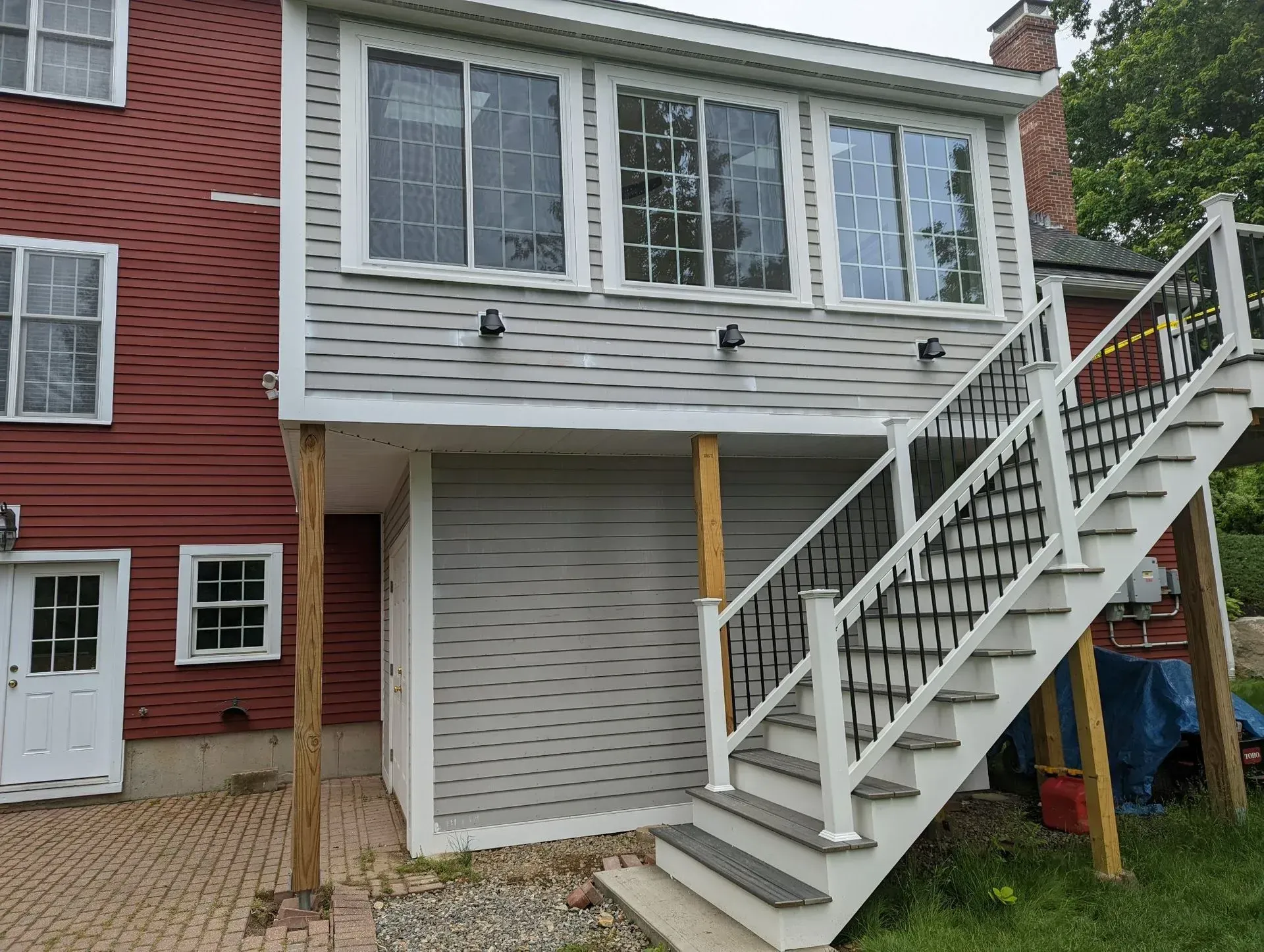 Back stairway leading to a gray-sided house with white railings and red brick exterior
