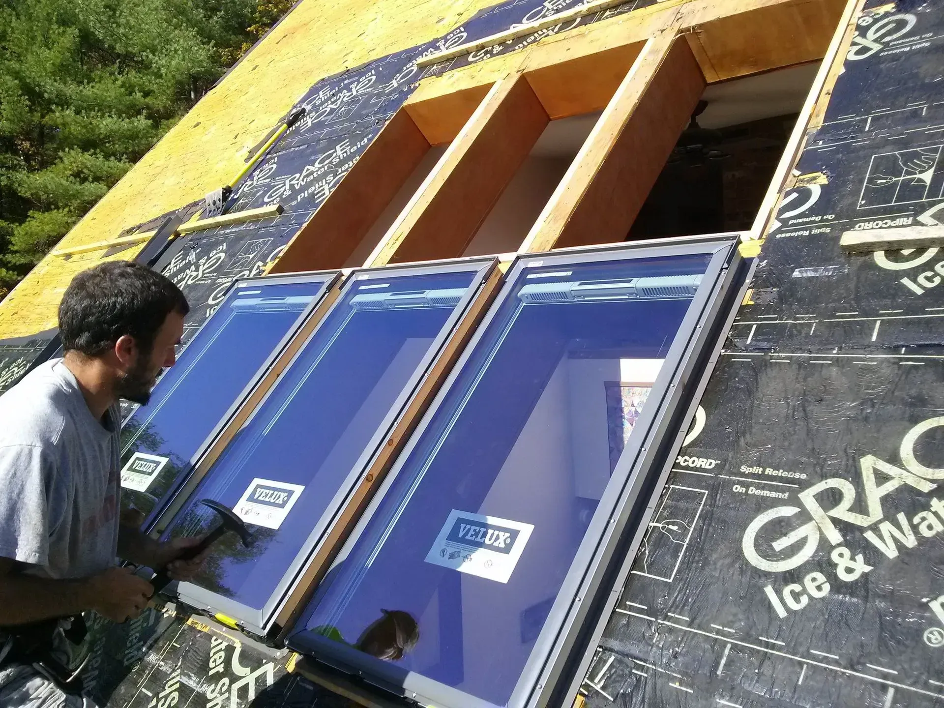 Worker installing blue-framed windows on a house under construction