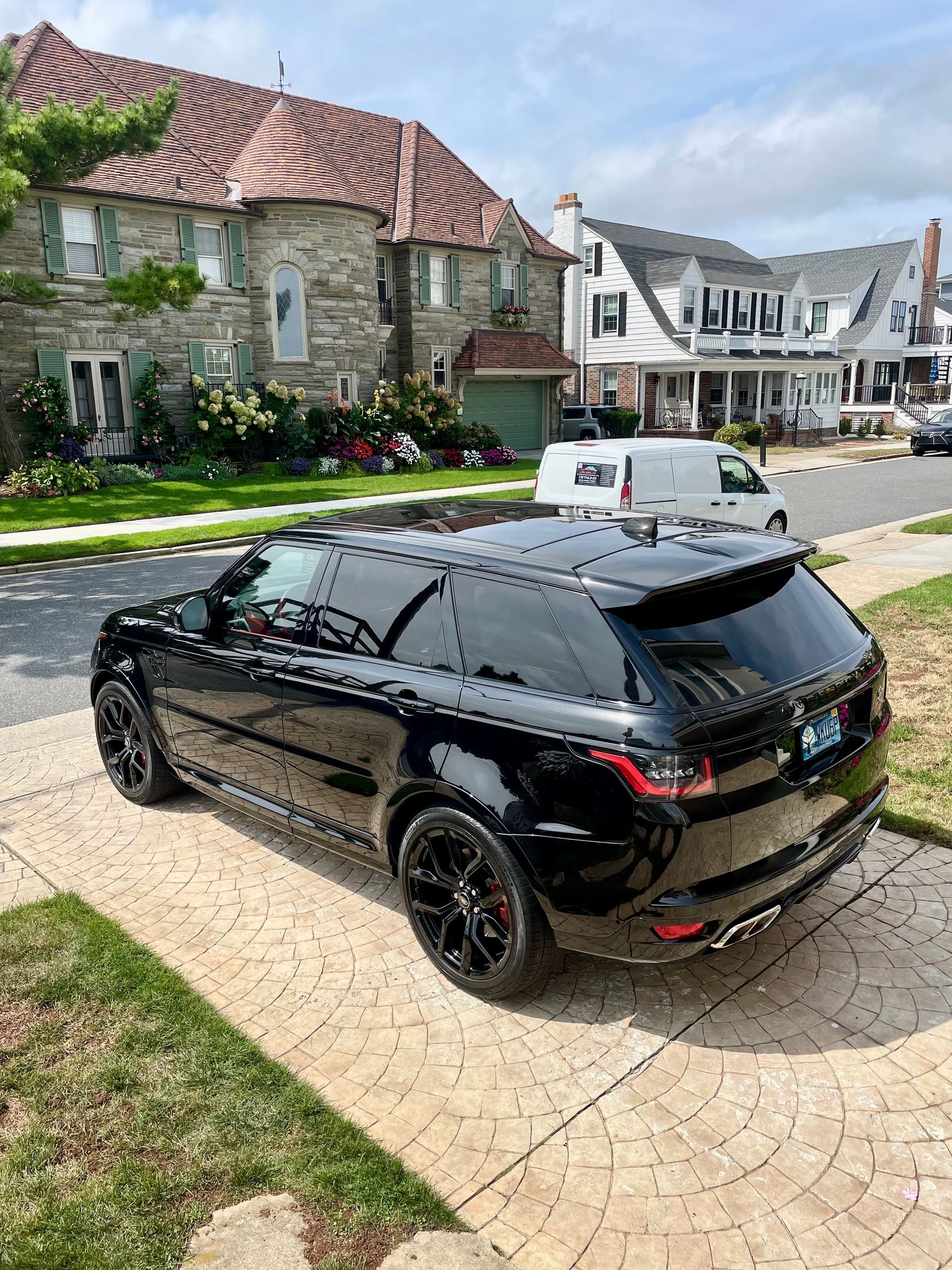 Black SUV parked on a cobblestone street beside stone houses and white buildings in a village.
