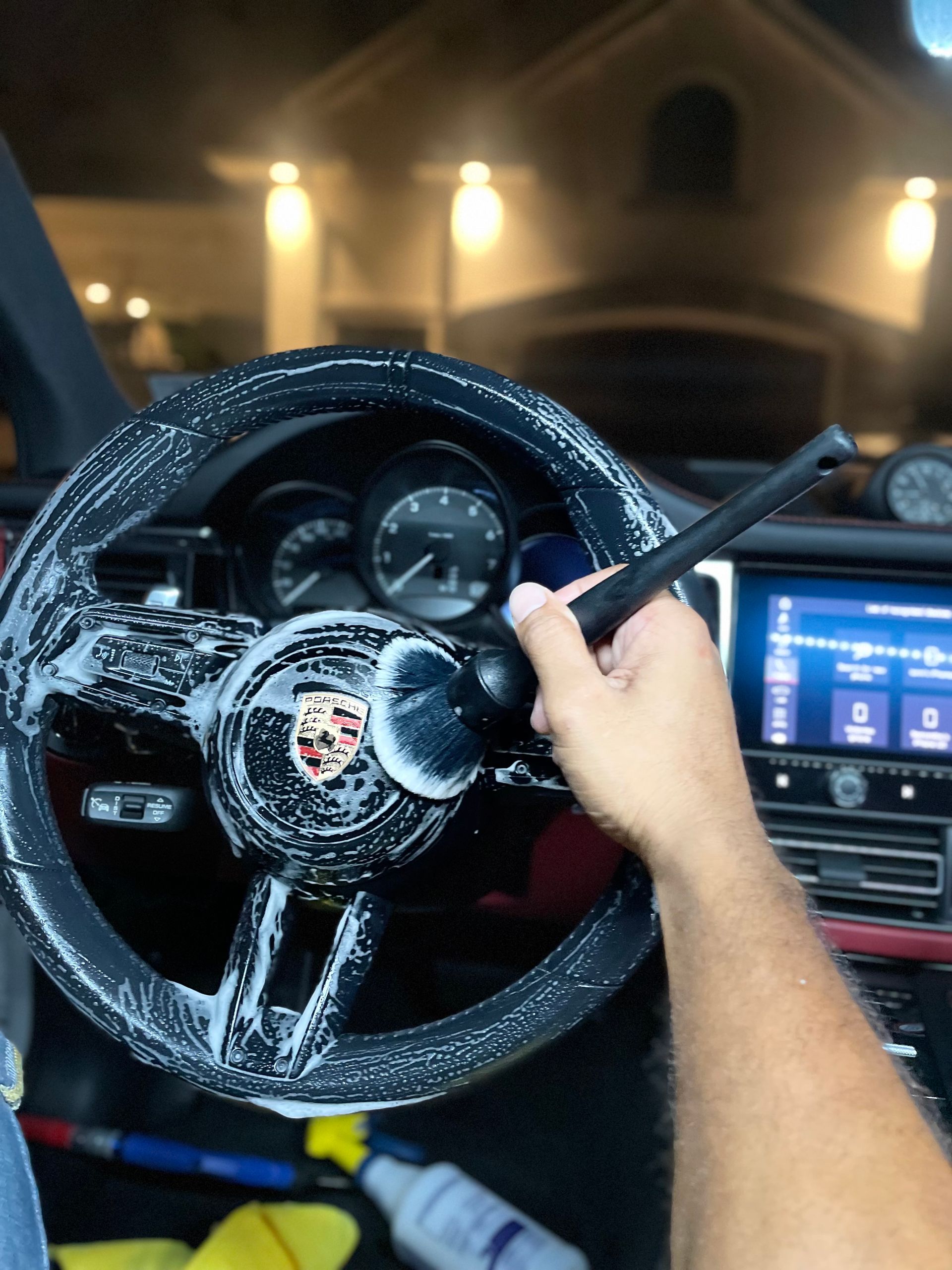 Driver’s view of a Porsche steering wheel with a hand holding the gear lever at night