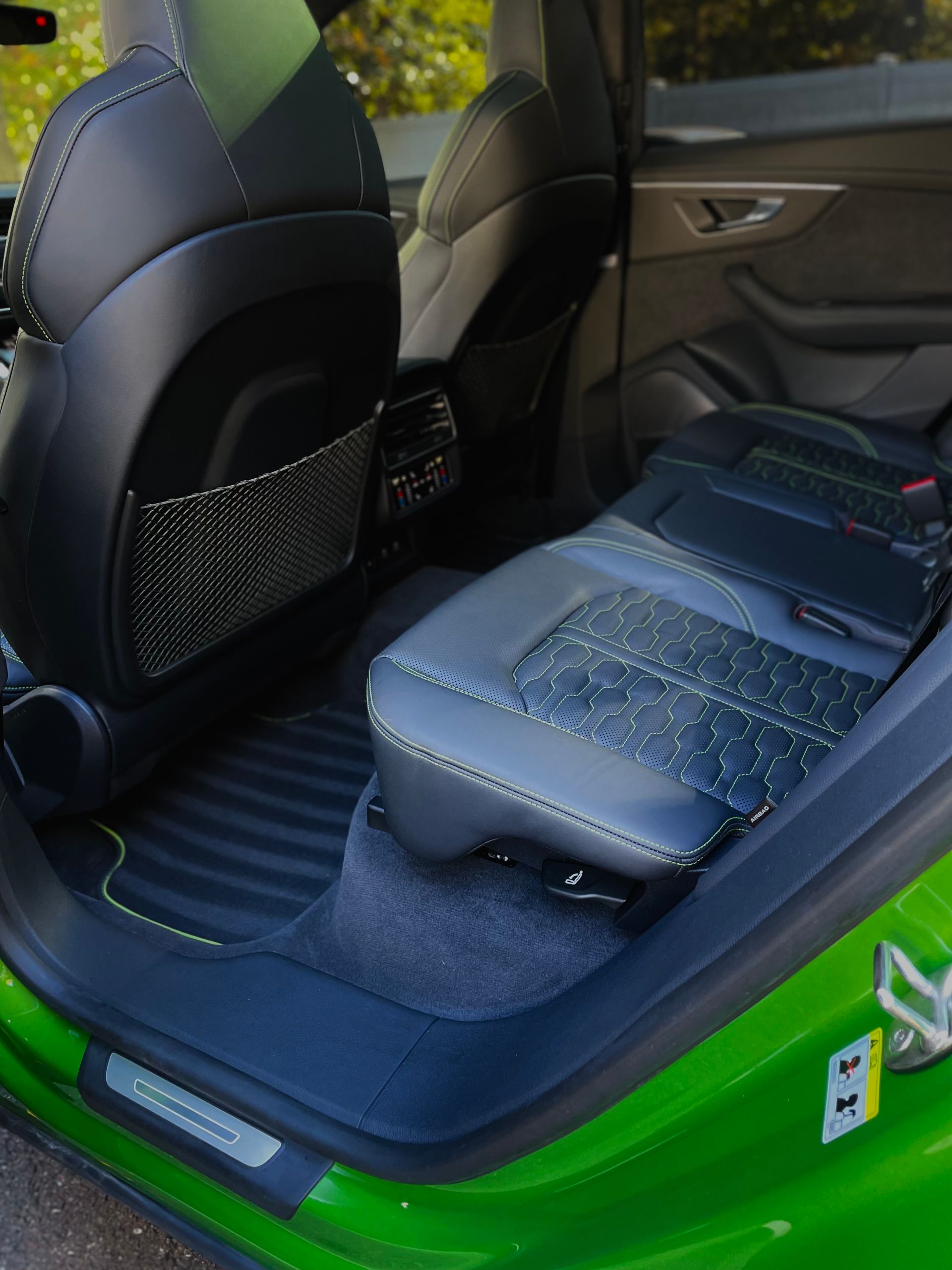 Car interior with wet black and blue seats and green door frame, viewed from the open rear door