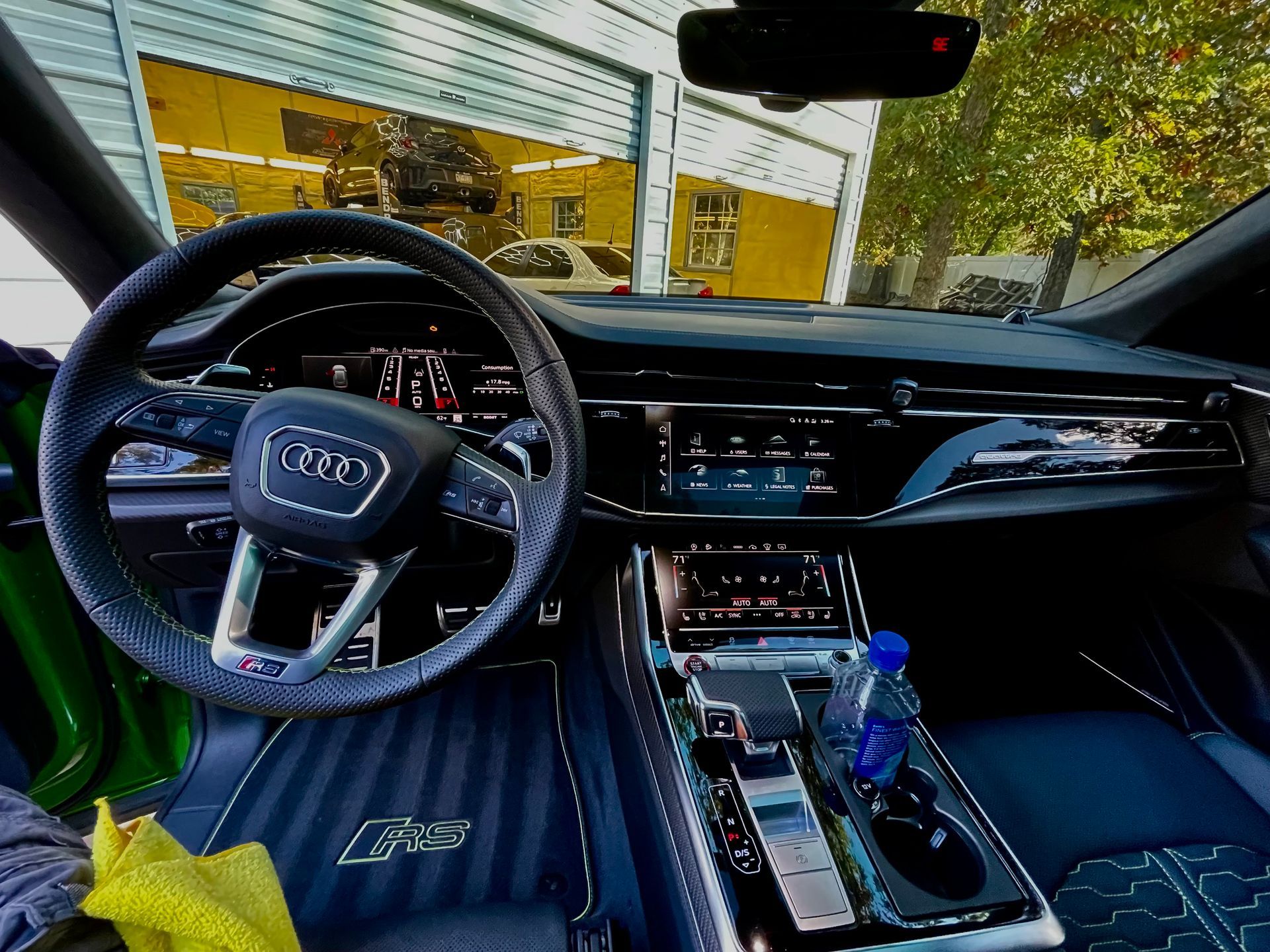 Interior of a modern Kia car with blue seats, steering wheel, and center console, parked by a building.