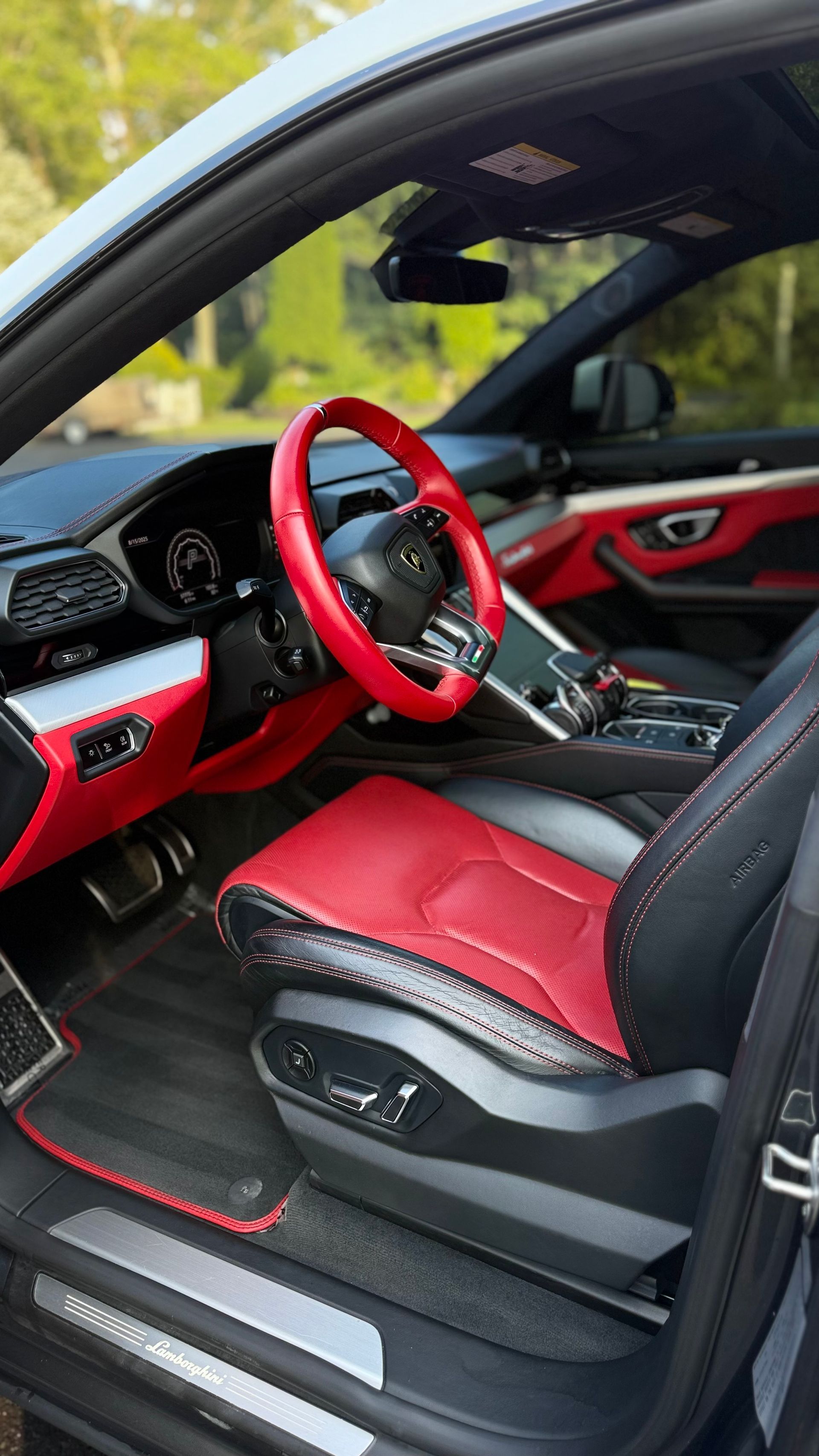 Red and black car interior with customized steering wheel and seats, viewed through the open door