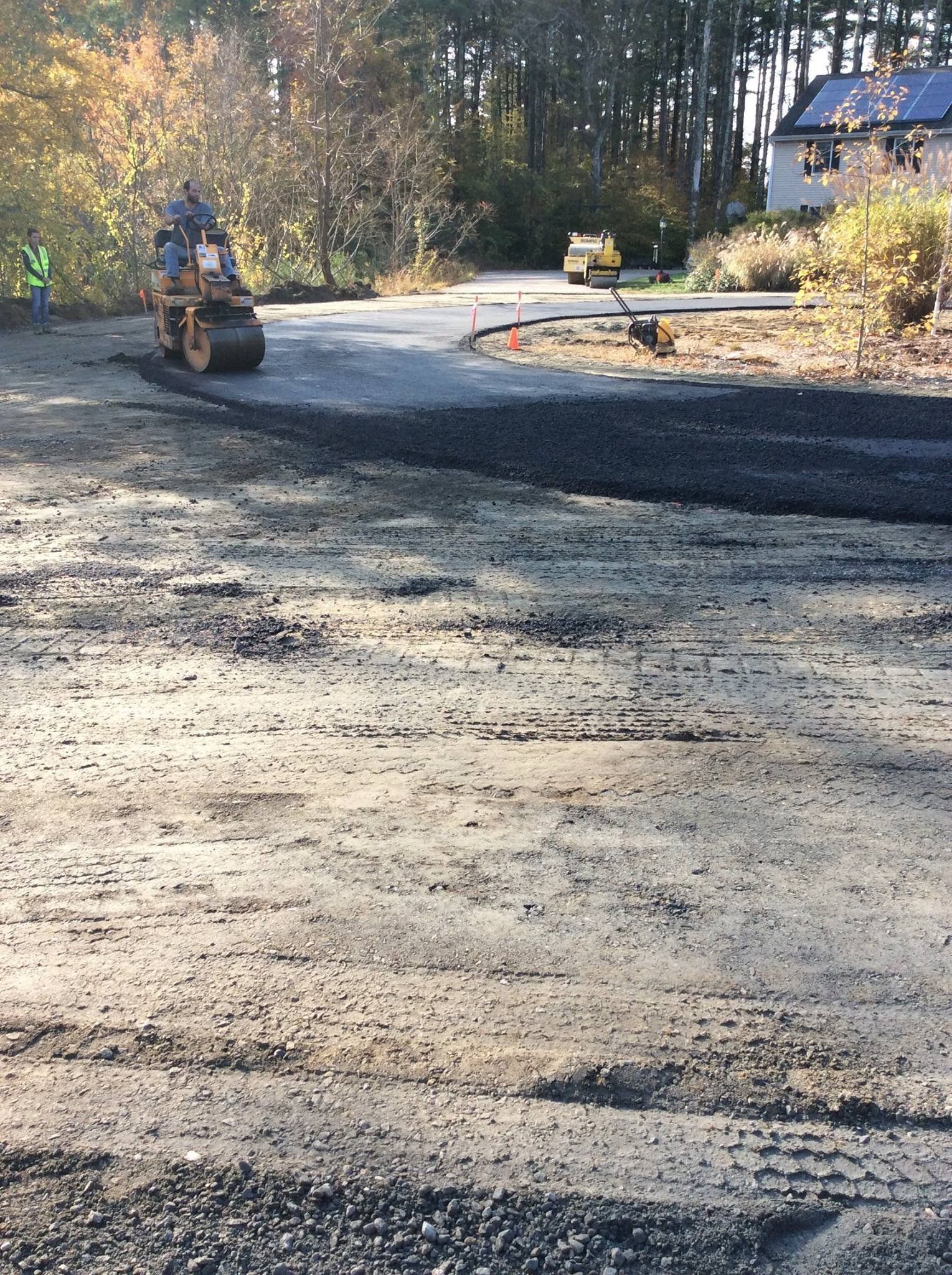 A man is driving a bulldozer down a dirt road.