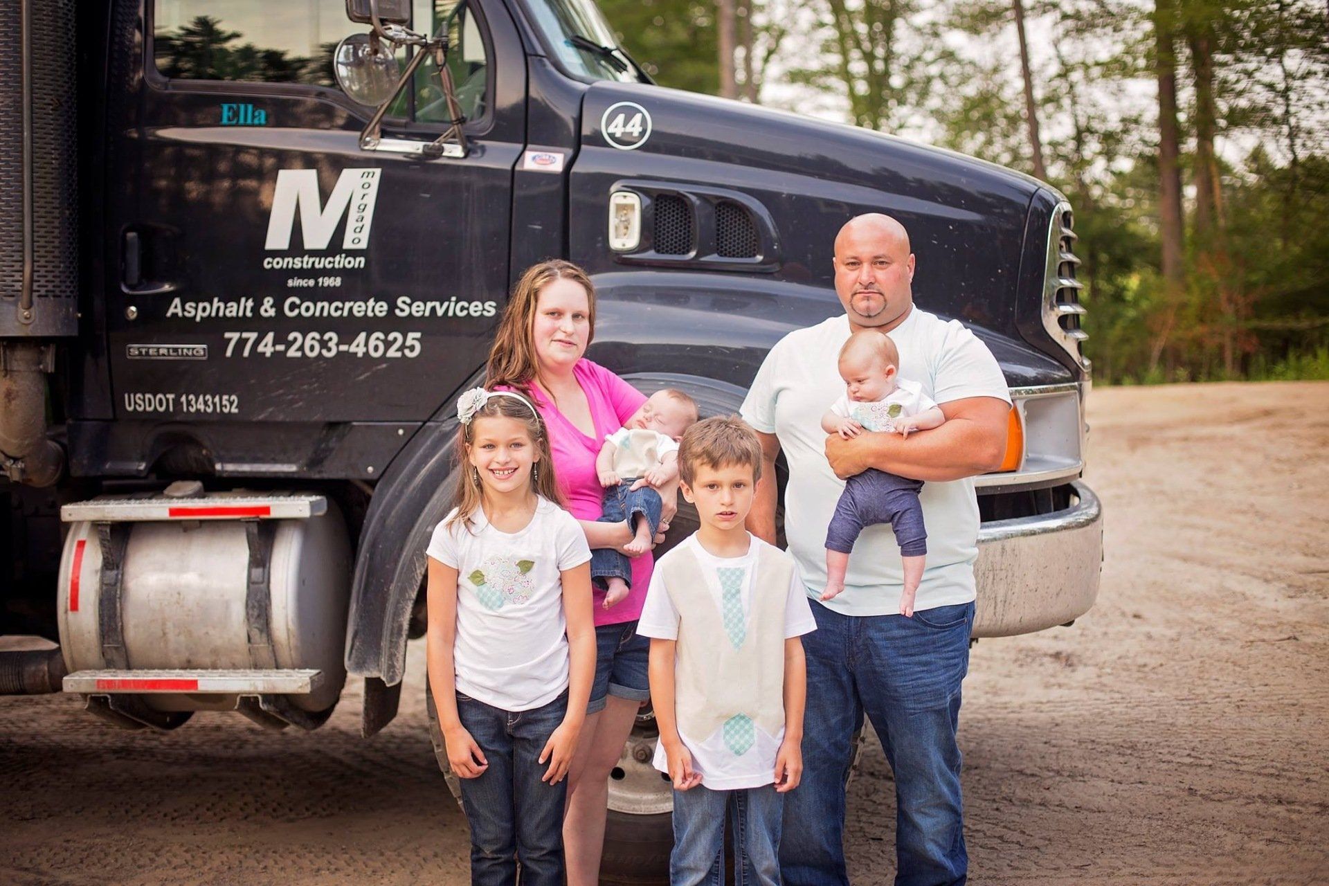 A family is posing for a picture in front of a truck.