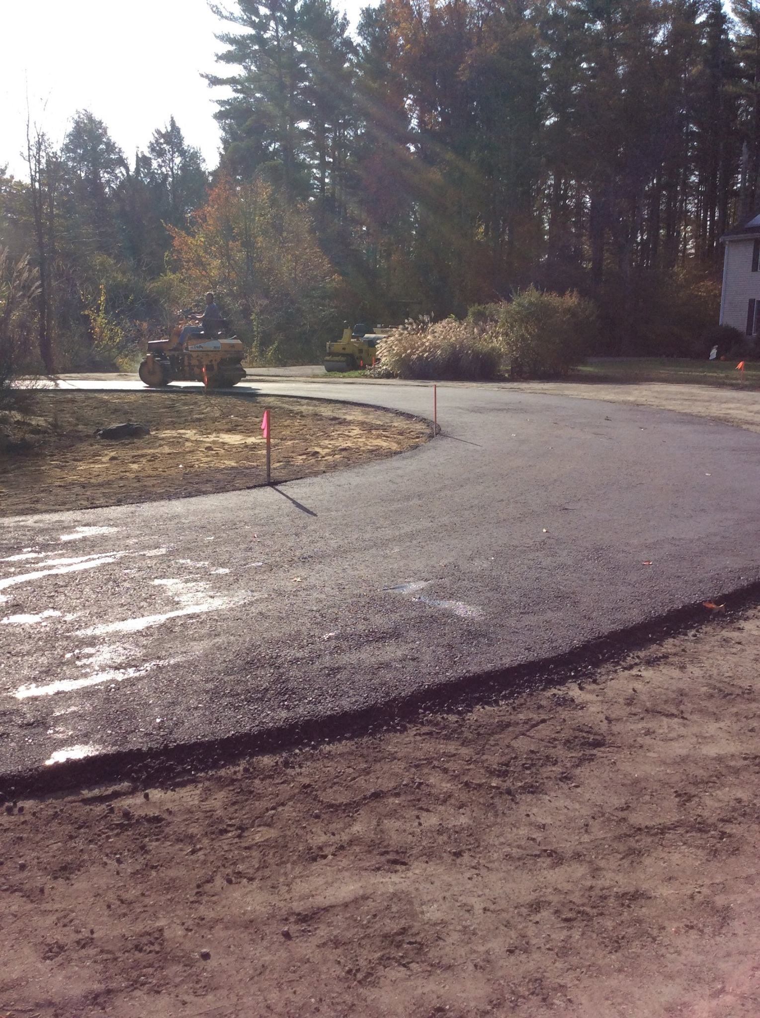 A tractor is driving down a road with trees in the background