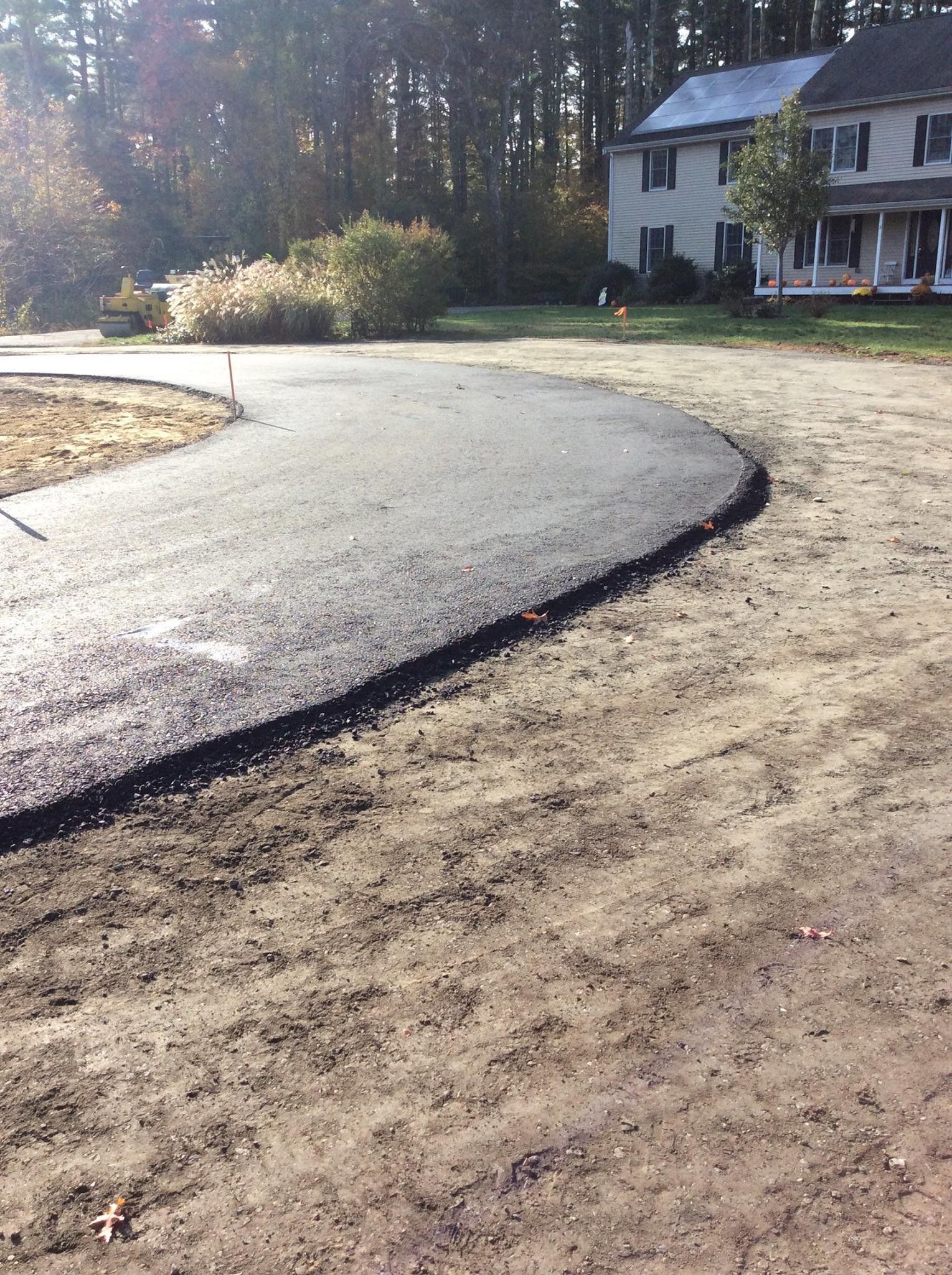 A curved driveway leading to a house with trees in the background