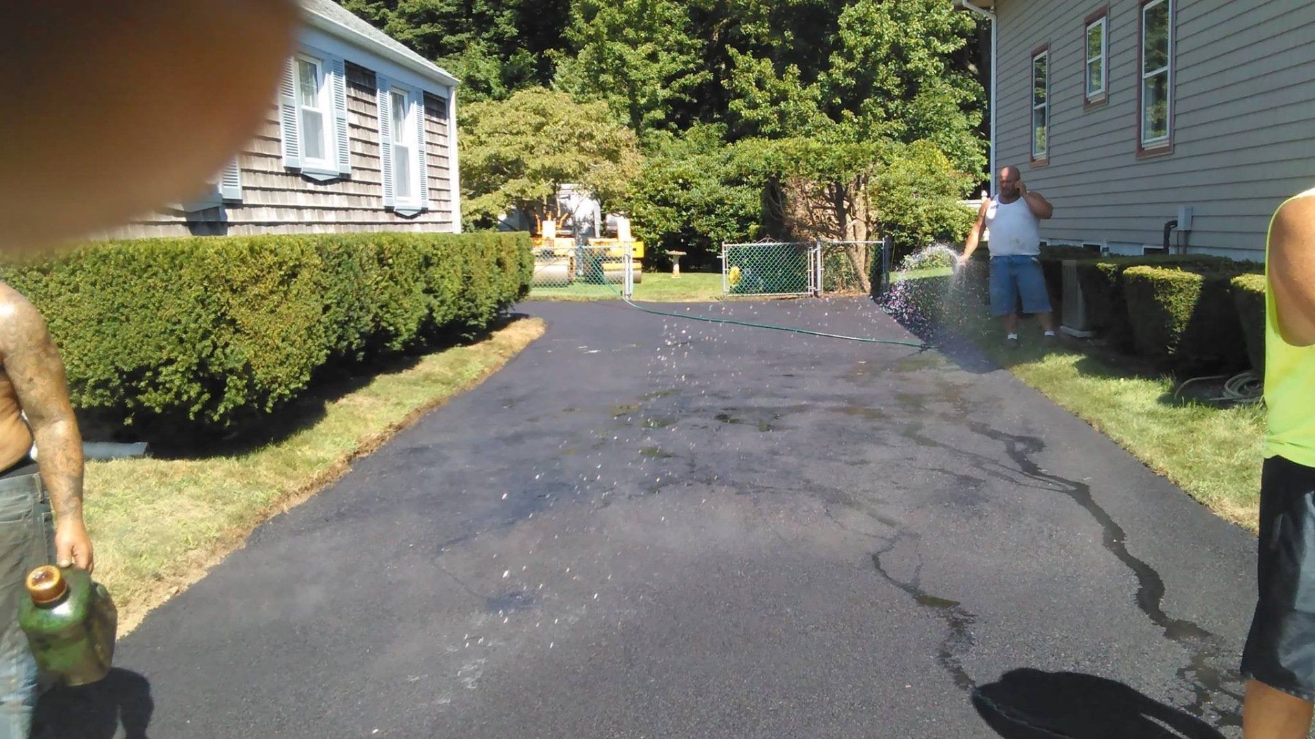 A group of people are standing on a driveway in front of a house.