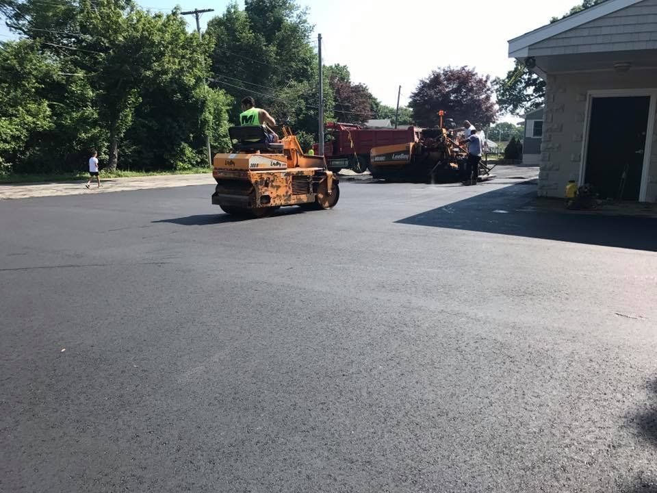 A tractor is driving down a road next to a house