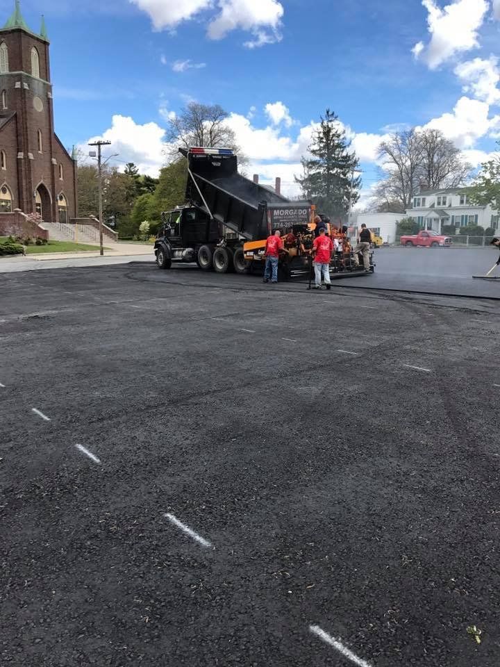 A group of people standing next to a dump truck in a parking lot.