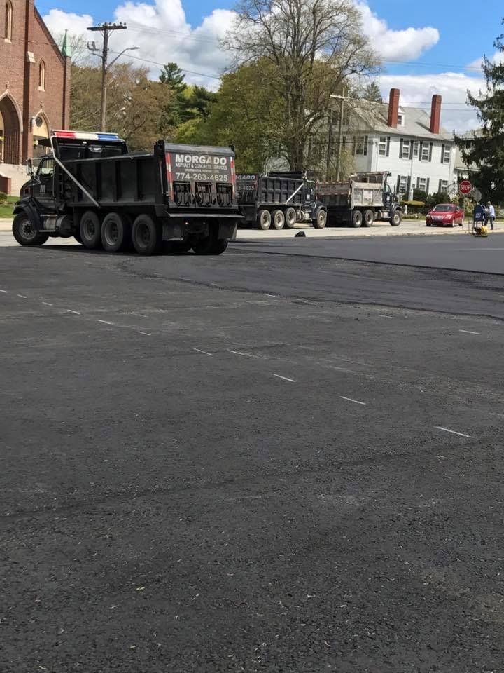 A dump truck is driving down a street in a parking lot