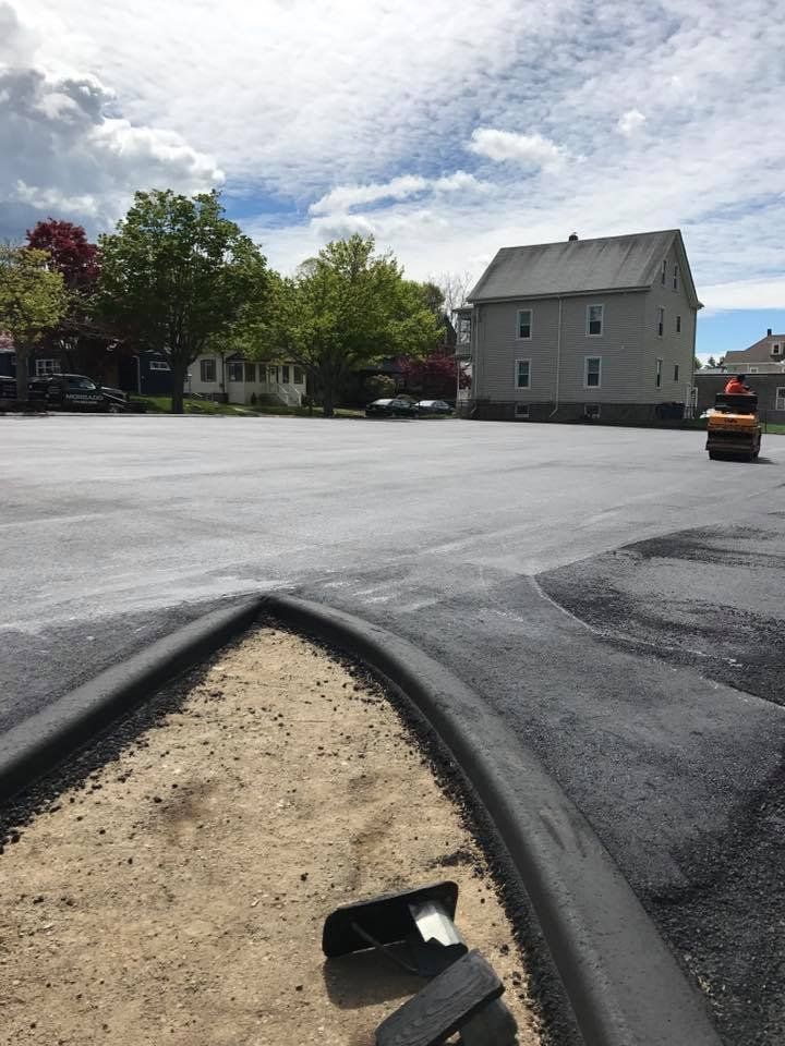 A large empty parking lot with a house in the background