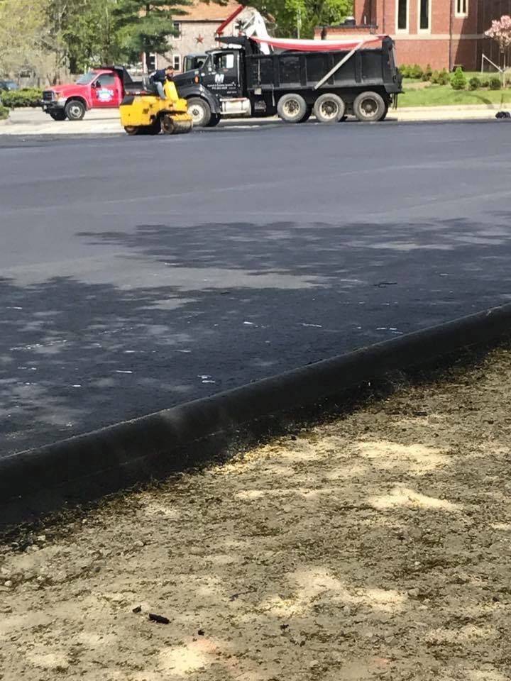 A dump truck is driving down a road next to a tractor.