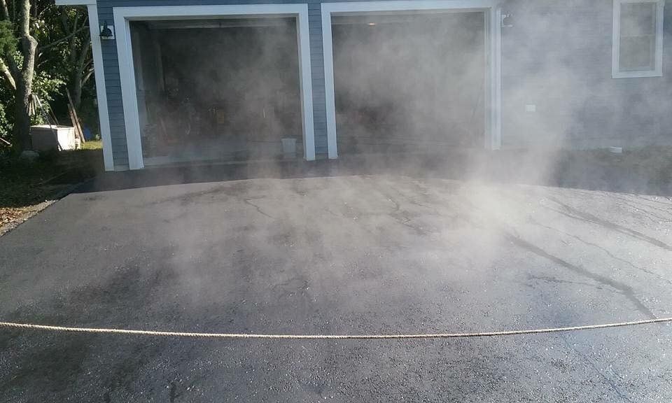 A driveway with smoke coming out of it in front of a house.