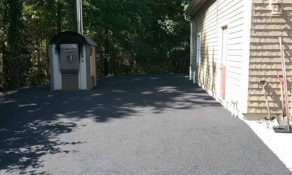 A driveway leading to a house with a shed in the background