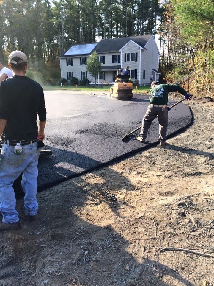 A group of men are working on a road in front of a house.