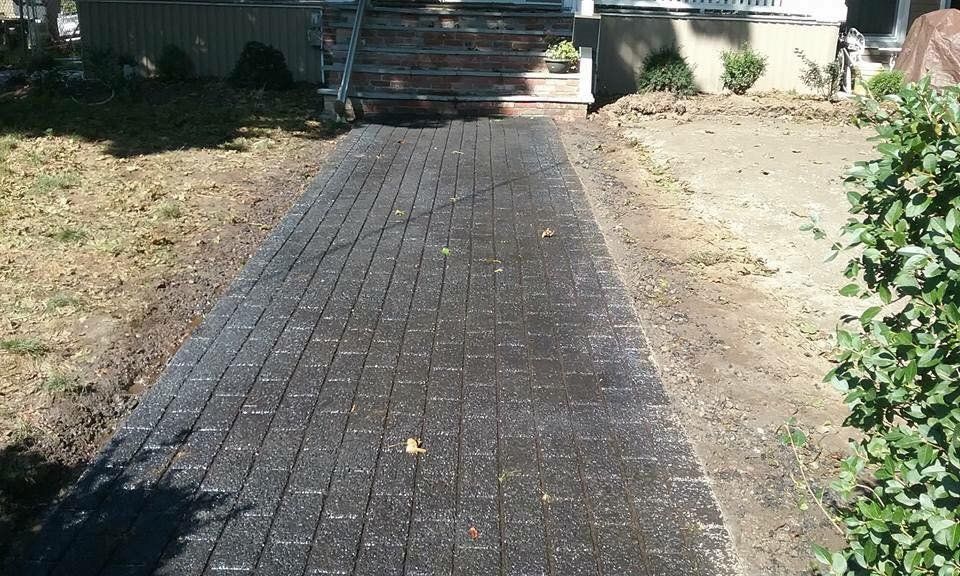 A brick walkway leading to a house with stairs.