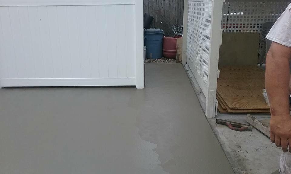 A person is standing on a concrete floor next to a white fence.