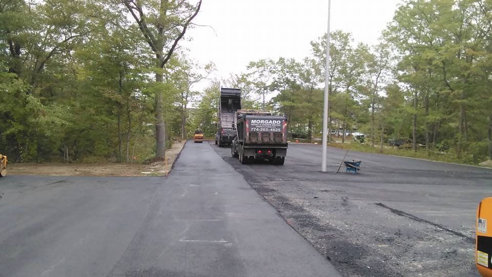 Two dump trucks are parked on the side of a road.