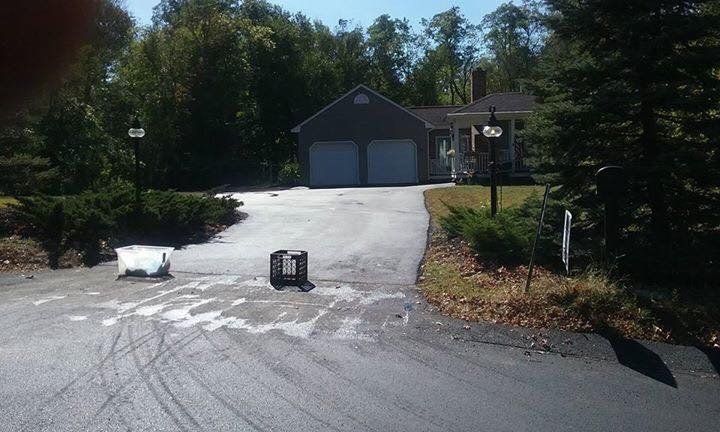 A house with a driveway and a garage is surrounded by trees.