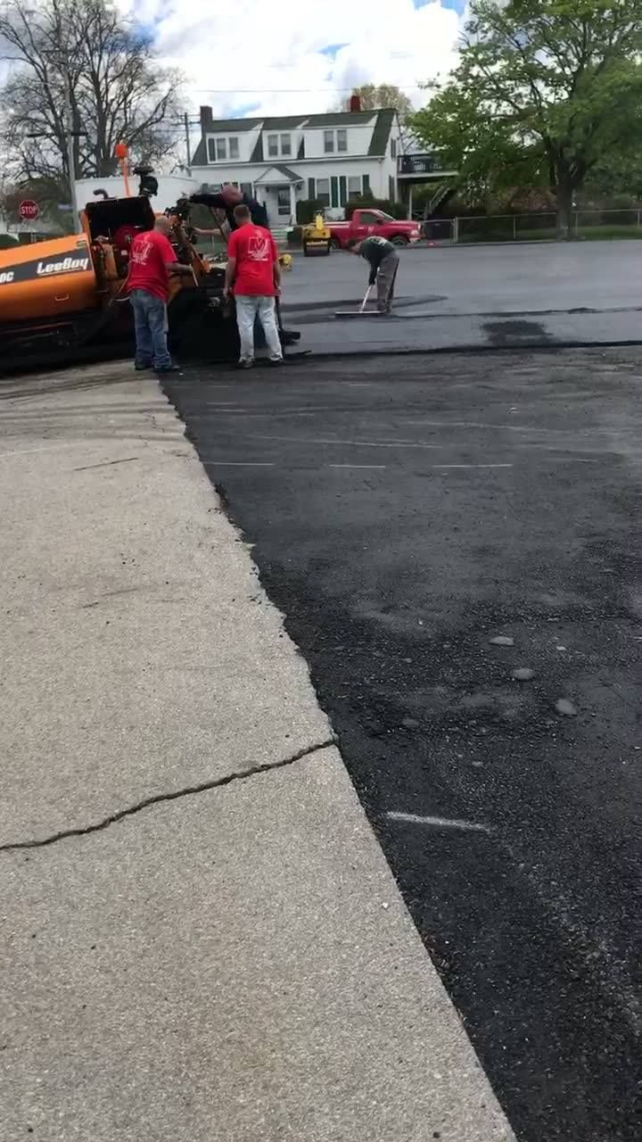 A group of people are standing next to a car in a parking lot.