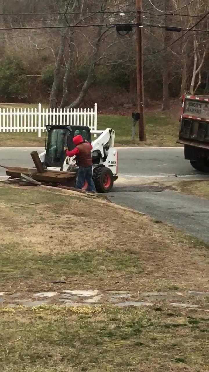 A man is standing next to a bulldozer on the side of the road.