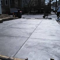 A concrete driveway is being built in front of a house.