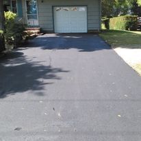 A driveway leading to a house with a garage door.