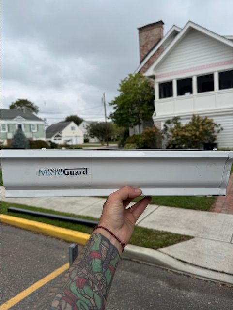 A person holds a white gutter guard with 