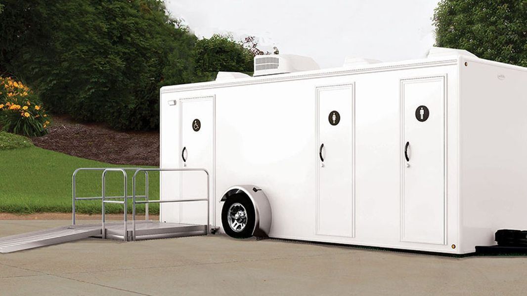 White portable restroom trailer with ramp for accessibility.