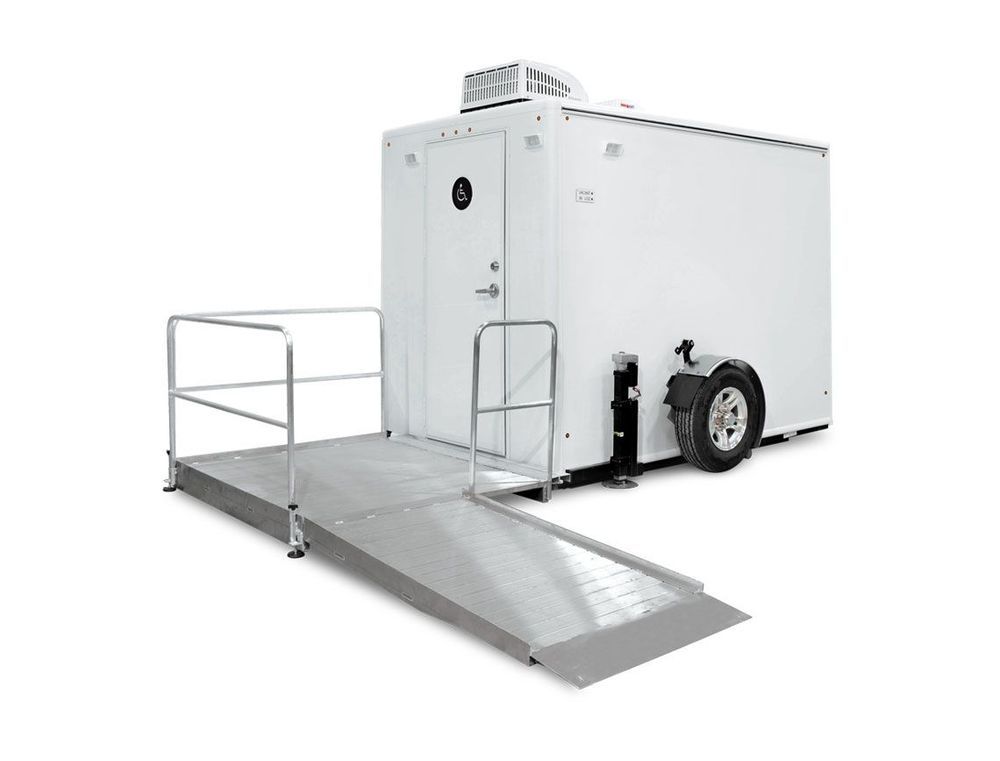 White mobile restroom trailer with ramp for accessibility.