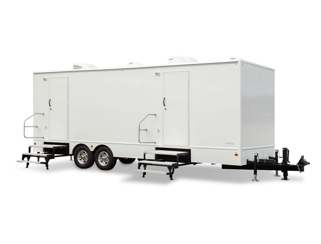 White restroom trailer with two entry doors, stairs, and wheels.