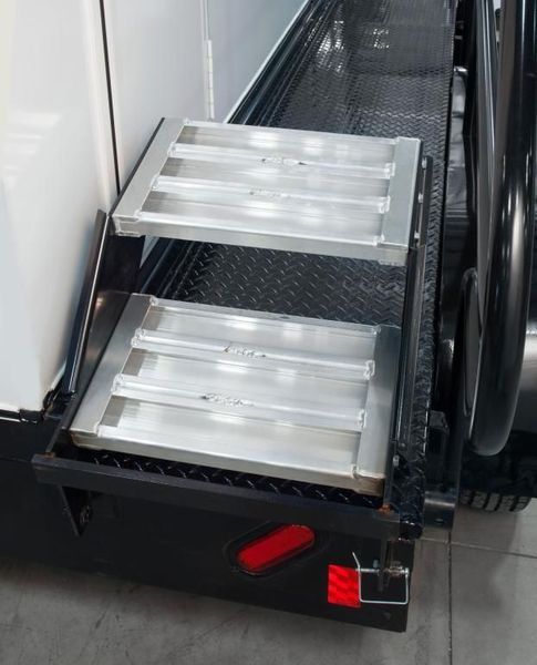 Two metal steps attached to a black truck, with a red reflector.