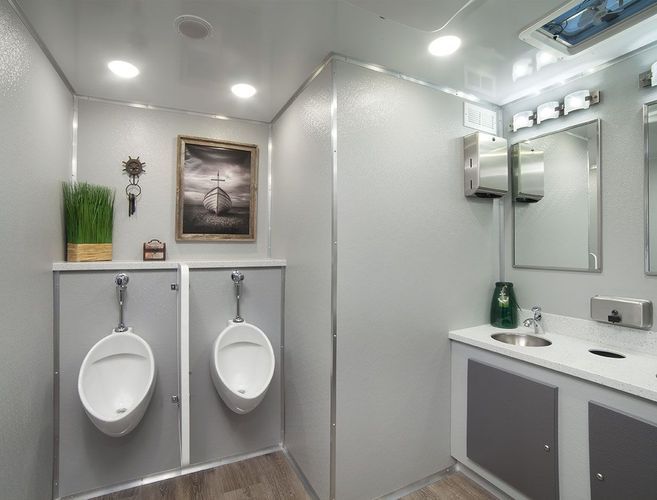 Inside of a portable restroom with two urinals and a sink area.
