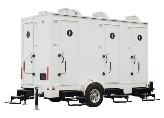 White portable restroom trailer with three stalls and steps.
