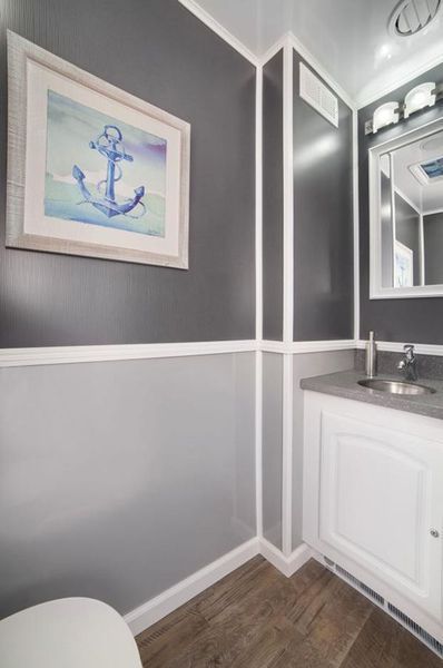 Bathroom interior with gray and white walls, anchor art, sink, and toilet.