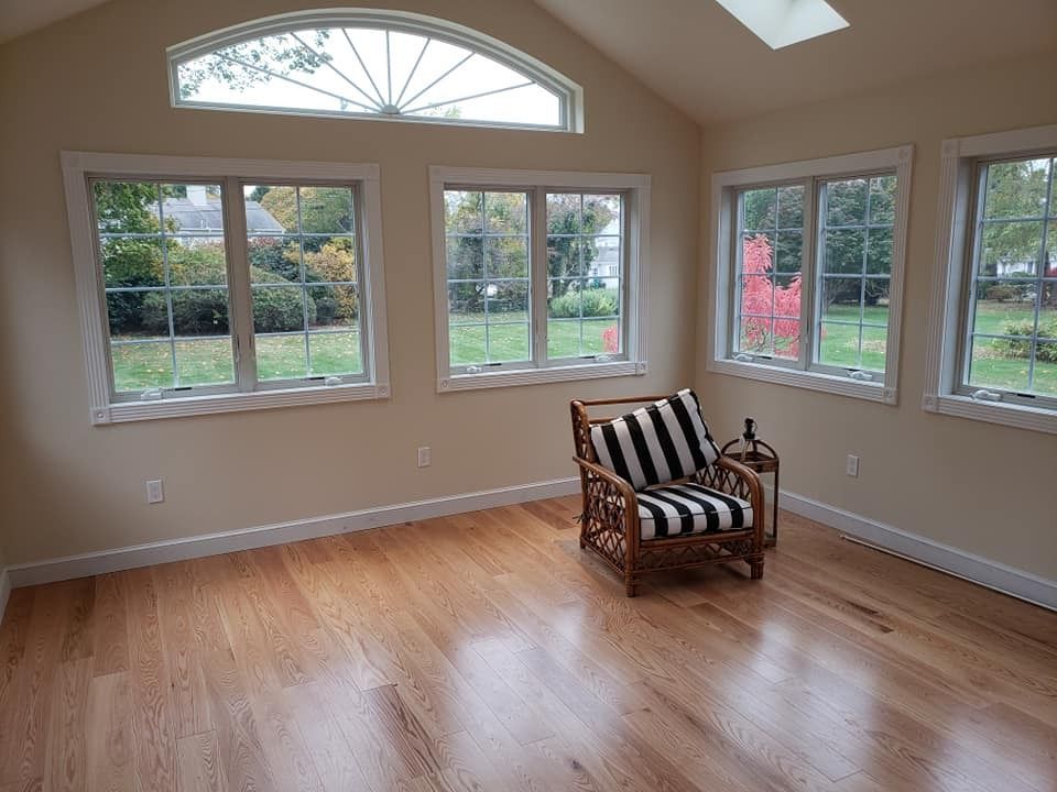 Sunroom with hardwood floor, windows, and a black and white striped armchair.